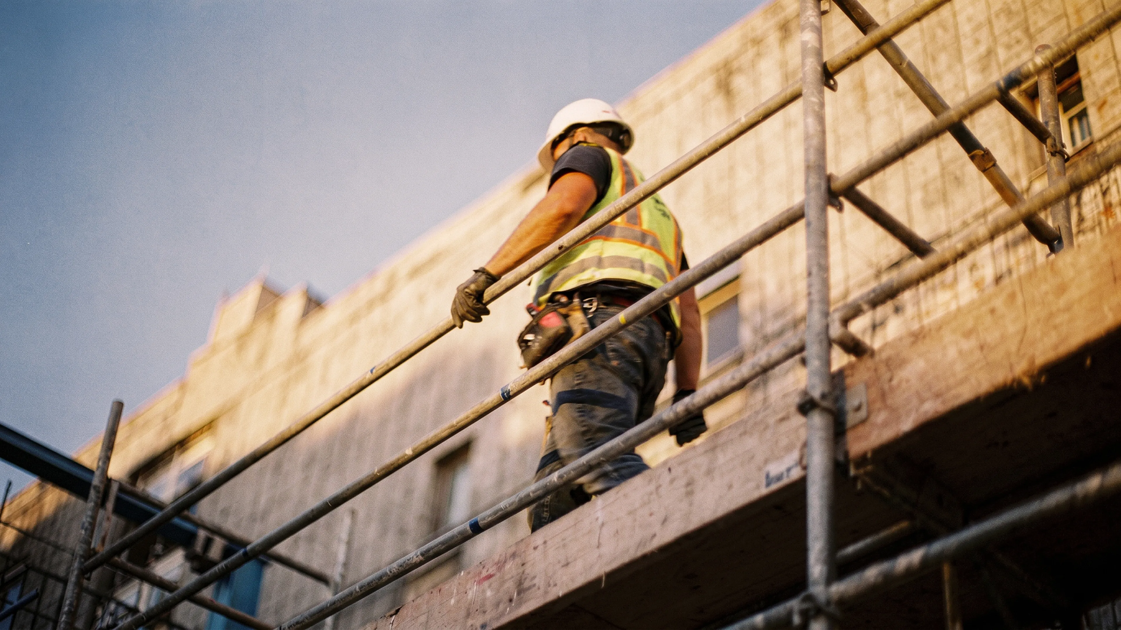 Ein Bauarbeiter auf einem Gerüst bei der Arbeit an einer Gebäudefassade – Sinnbild für körperliche Arbeit und den Wandel der Arbeitswelt.
