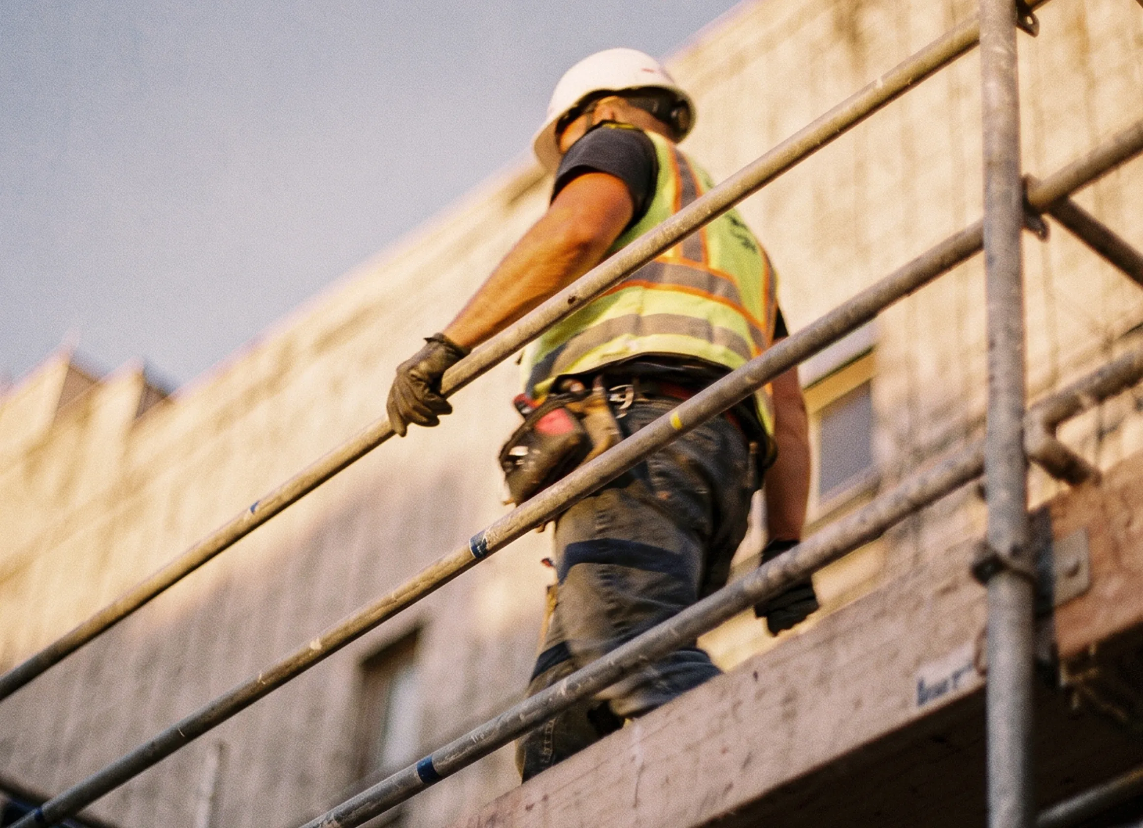 Ein Bauarbeiter auf einem Gerüst bei der Arbeit an einer Gebäudefassade – Sinnbild für körperliche Arbeit und den Wandel der Arbeitswelt.